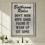 Unframed stretched canvas print of a humorous Bathroom Rules sign with distressed white background and bold black stencil lettering listing Don't Miss Wipe Good Flush It Wash Up Git Gone above a modern bathroom vanity