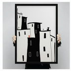 Hand-held black framed poster print of minimalist black and white building silhouettes with black cat on rooftop and small red door detail