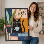 Smiling woman in a cream sweater holding a large vertical black framed bohemian collage black cat coffee canvas art print showing a relaxed black cartoon cat cradling a steaming blue and white striped mug beside a large leafy plant in a dark blue pot on a vibrant patchwork background of pink, navy, orange, and cream geometric panels with dot and stripe patterns and hanging green leaf sprigs in a bright plant-filled room