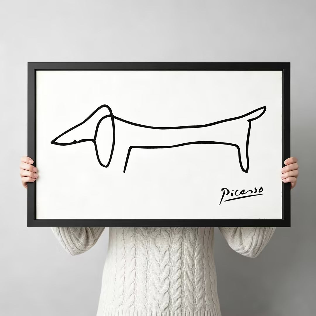 Picasso-inspired minimalist dachshund single-stroke line art in black wood frame held up against a light gray backdrop, white background canvas print
