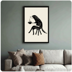 Black-framed quirky dog drinking coffee art print hung above a neutral linen sofa on a muted sage green wall