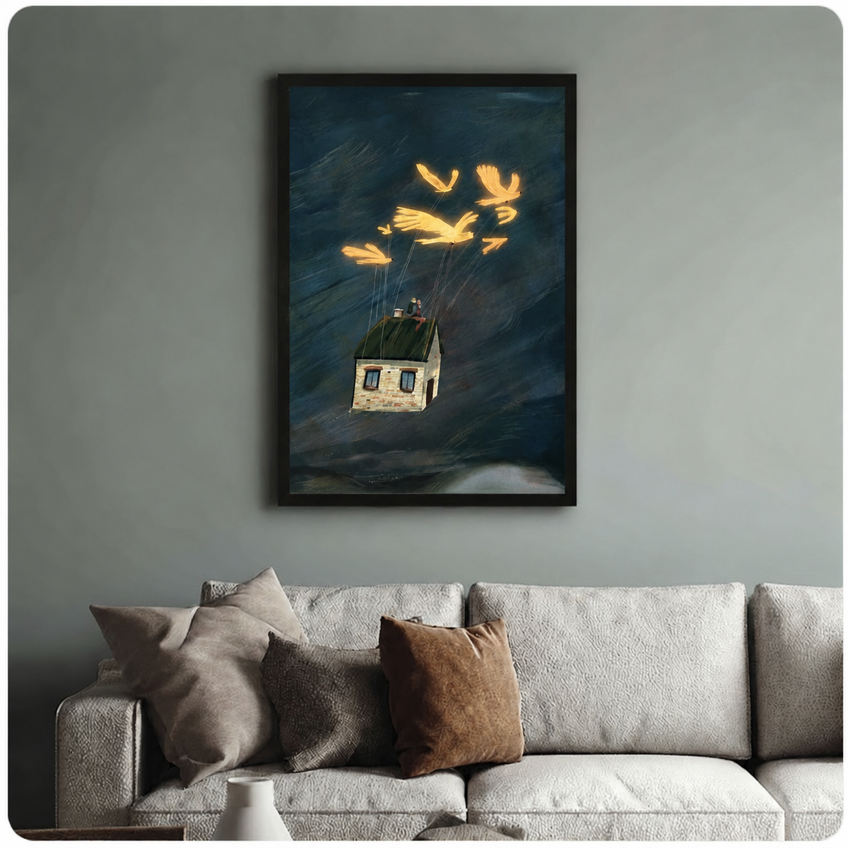 Whimsical framed wall art print of glowing birds tethered to a drifting house above stormy waters, styled above a neutral linen sofa