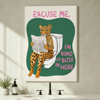 Gallery-wrapped canvas art of a cartoon leopard sitting on a toilet reading a newspaper, hung unframed above a bathroom vanity with black fixtures and potted green plants