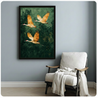 Pair of golden cranes with red crown gliding over lush green forest, black framed nature art print beside white armchair in bright minimalist room