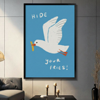 Funny "Hide Your Fries" seagull wall art print with blue background, white gull carrying a chip in its beak, displayed in black frame on dark grey wall