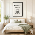 Black framed minimalist but first coffee sleepy dog canvas art with bold brush-lettered quote above a round cartoon dog with closed eyes hugging a coffee cup in loose black line art on a cream background, hung above a wooden bed frame in a sun-