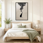 Black framed minimalist black cat smoking pipe canvas art with ornate smoke cloud above a bed with white linen bedding, a sage green throw blanket, light wood nightstands, potted plants, and a ceramic table lamp