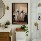 Framed penguin bathroom wall art showing two birds draped in white towels, displayed above toilet in a luxury marble bathroom with gold fixtures