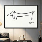 Picasso-inspired dachshund single-stroke sketch black framed canvas art mounted on dark gray paneled wall above charcoal sofa with brass candle holders, minimalist modern home decor