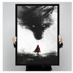 Two hands holding a large black-framed dark wolf and red riding hood art print, showcasing canvas size and dramatic ink illustration detail