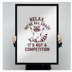 Person holding a black framed art print featuring a raccoon illustration and the humorous quote Relax We're All Crazy It's Not A Competition against a neutral gray background