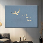 Gallery wrap stretched canvas of a flying white seagull with Hide Your Fries handwritten quote on a powder blue background hung frameless on a dark gray paneled wall above candlestick holders