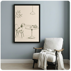 Black framed minimalist pencil sketch dachshund with oversized nose sniffing cafe croissant and coffee canvas art on cream background on a soft blue-gray wall beside a white wood folding armchair with a cream linen throw blanket