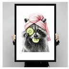 Pencil sketch raccoon with pink towel turban and cucumber slices wall art print in a black frame held up against a light grey backdrop, full front view of funny animal spa poster print