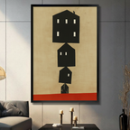 Black framed canvas print of stacked minimalist black house silhouettes on beige background with red base, displayed on dark wall above console table