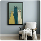 Vertical framed canvas of three abstract mid-century cats in mustard, teal, and cream tones, hung on a blue-grey wall beside a linen accent chair with a draped throw