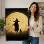 Person holding a large vertical black framed vintage little witch and black cat under a full moon canvas art print showing a witch in a pointed hat and a black cat standing in tall grass gazing at a huge golden moon with bats in a textured sepia sky in a bright plant-filled room