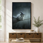 Framed gothic wall art print of a fluffy gray cat wearing a witch hat riding a broomstick, displayed above a wicker console table in a bright entryway